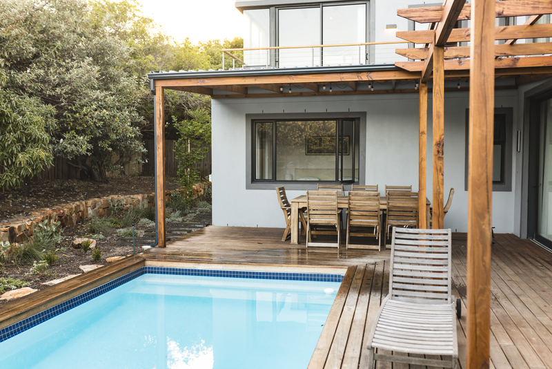 Patio trasero de una casa con alberca y detalles en madera